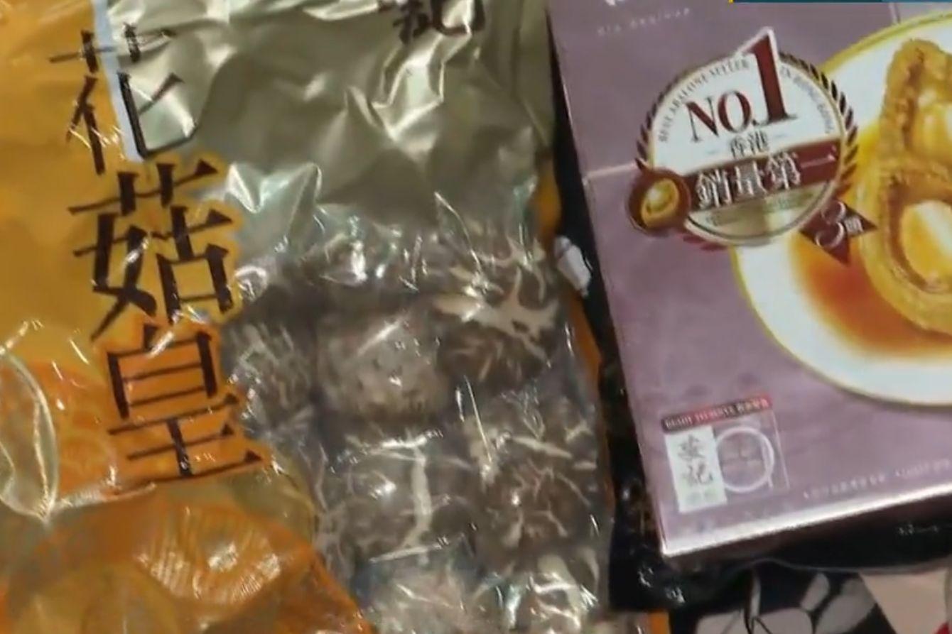 逸葵樓居民離開時獲發一份福袋,內裡有鮑魚、冬菇及臘腸等。(電視截圖)