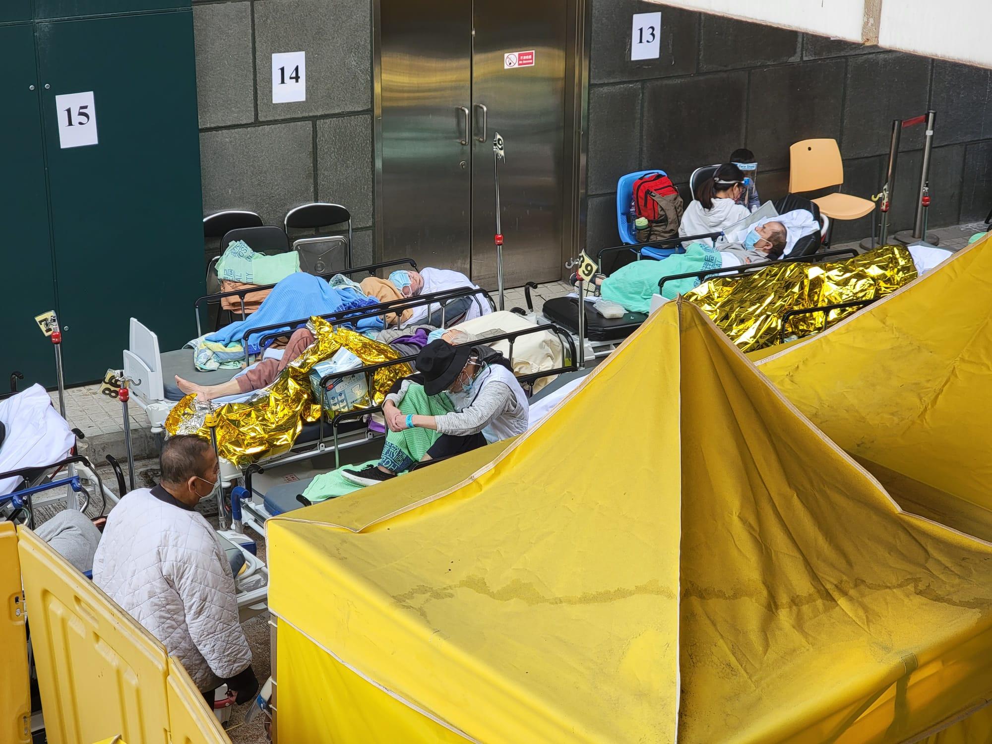在明愛醫院新冠患者分流站,約10名長者躺在帳篷外的病床上。(莊振邦攝)