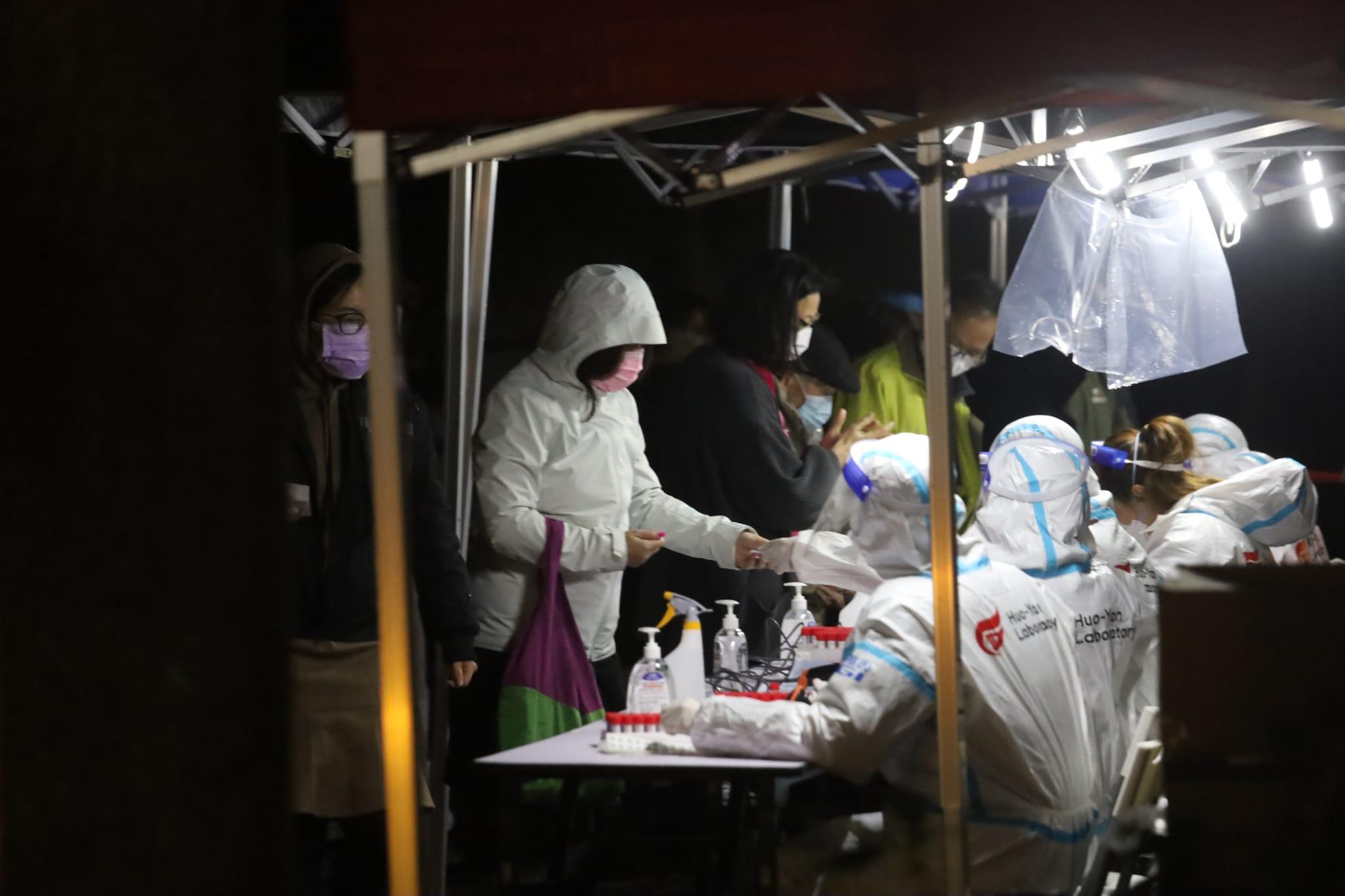 南昌邨圍封行動有工作人員身穿印有「火眼實驗室」標誌的保護衣。(鍾式明攝)