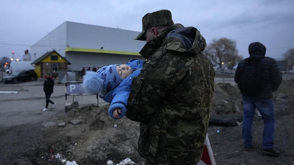 在波蘭邊境,波蘭士兵抱著烏國嬰孩。(AP)