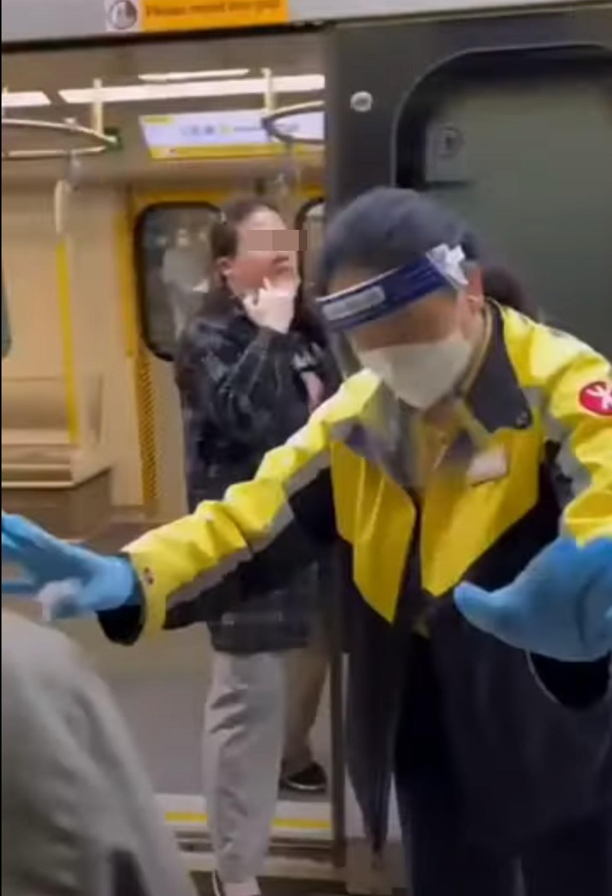 除罩的中年婦站在港鐵列車門口,不斷把口水鼻涕抹在車門周圍,並舉中指指向現場其他乘客。(網片截圖)