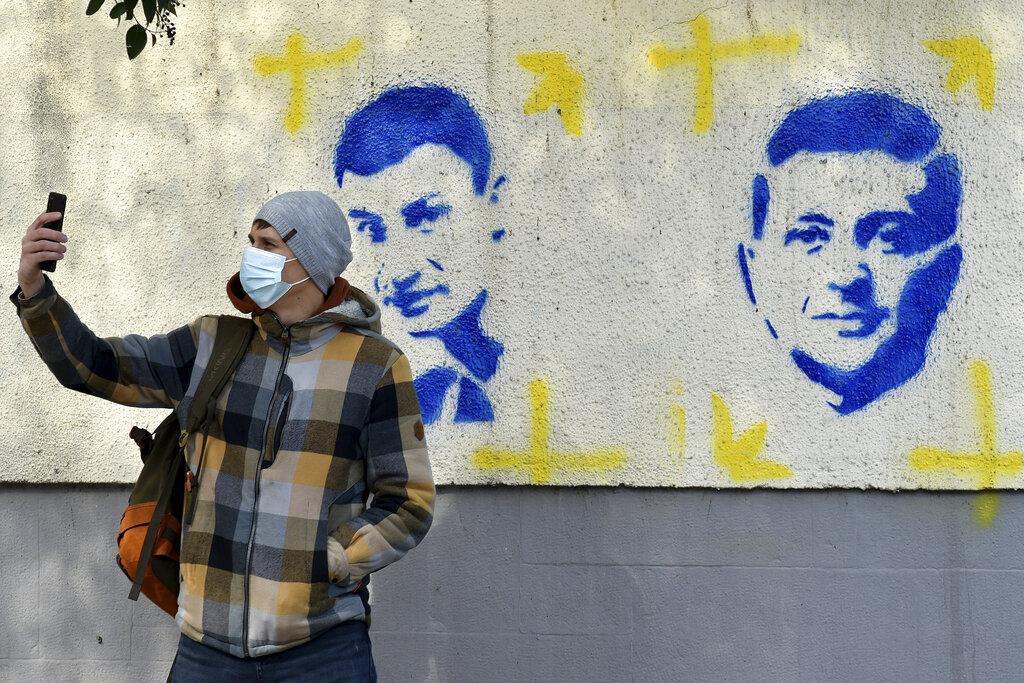 有民眾在烏克蘭總統澤連斯基圖像前自拍。(美聯社圖)