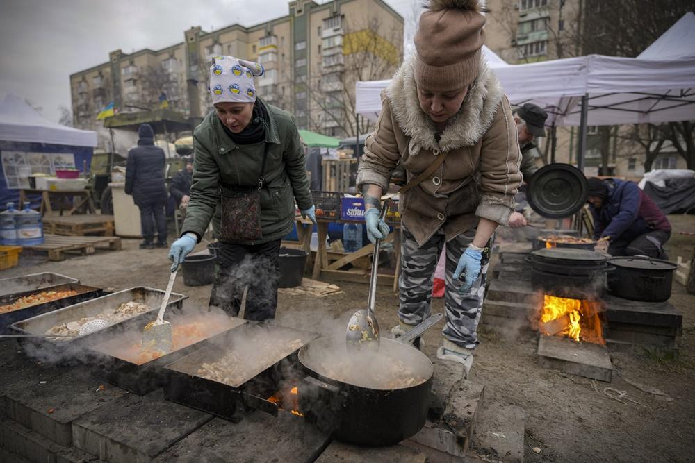 基輔民眾於戶外為義工抗戰人員煮食。(AP)