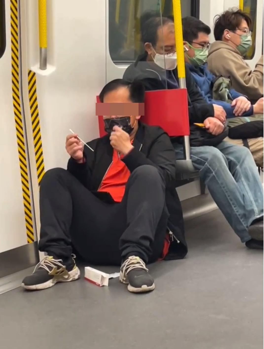 一名中年男子在港鐵車廂除口罩做快速檢測。(網片截圖)