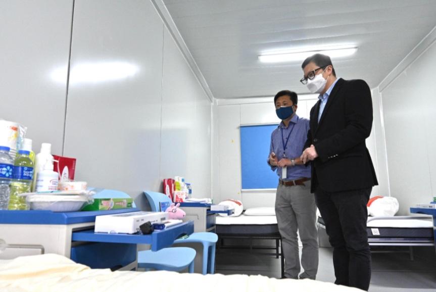 保安局局長鄧炳強今日(三月六日)視察中央援建位於青衣的社區隔離設施。圖示鄧炳強(右)聽取保安局首席助理秘書長(特別職務)謝振中(左)講解設施運作及物資準備情況。
