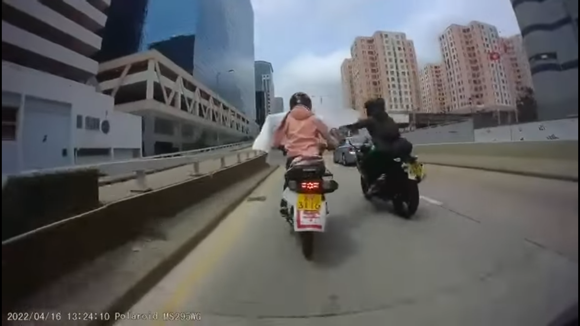 一名女騎士在九龍灣偉業街疑被路面垃圾阻礙,路過的另一名電單車司機協助拿走。(影片截圖)