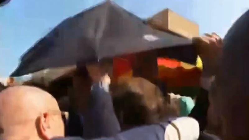 馬克龍險被民眾投擲的車厘茄擲中,在場保安一度開雨傘掩護。(Twitter)