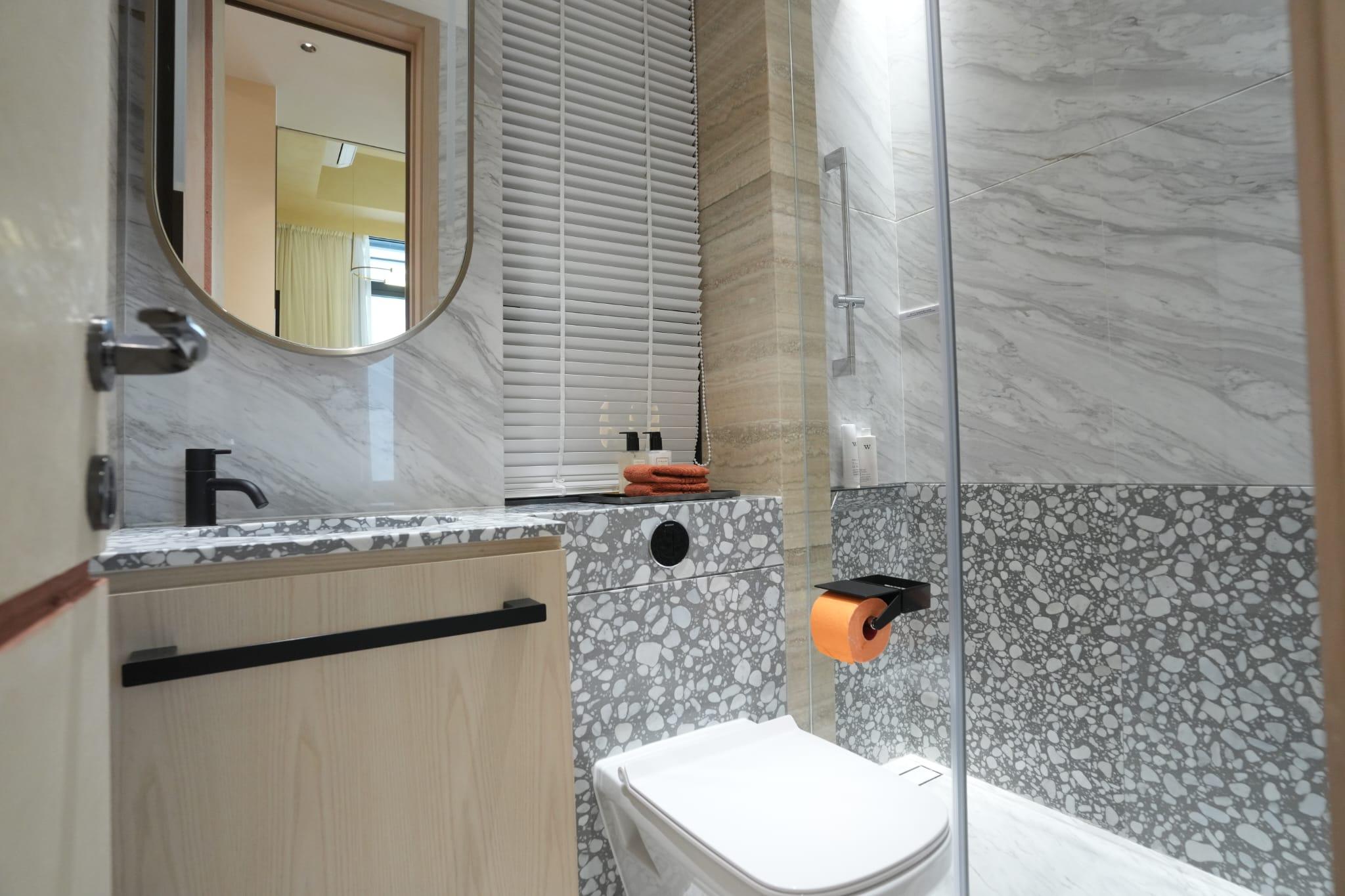 浴室以淺木色設計為主,選用丹麥Vola、德國DURAVIT及Hansgrohe衛浴配備,並裝設鏡面多用途儲物櫃連USB充電位。