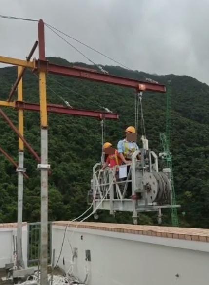 兩名工人將吊船移出大廈外並進行下降。(FB)