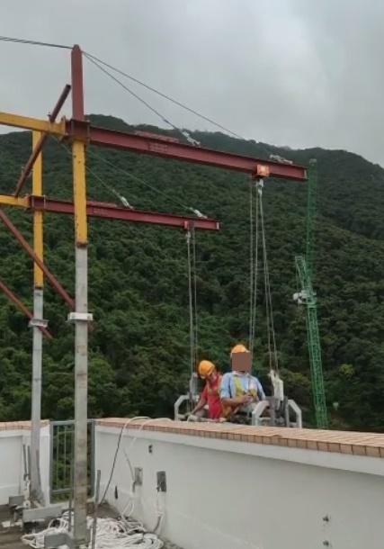 兩名工人將吊船移出大廈外並進行下降。(FB)