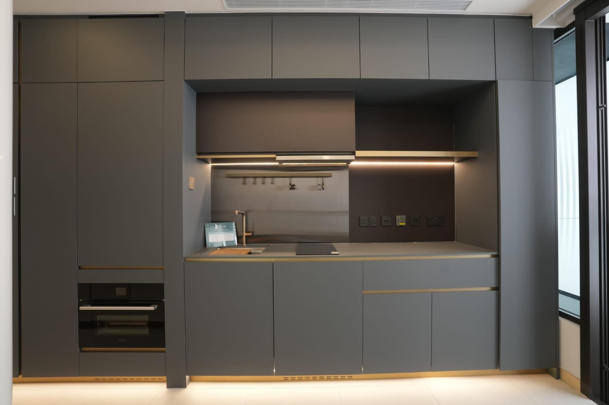 大型組合櫃與開放式廚房以一體化呈現,提供掛衣空間、衣物收納、儲物間隔、電視櫃、推拉式枱面,以及廚櫃、各種下廚家具和家電,一體式的設計貼心又實用。(陳奕釗攝)