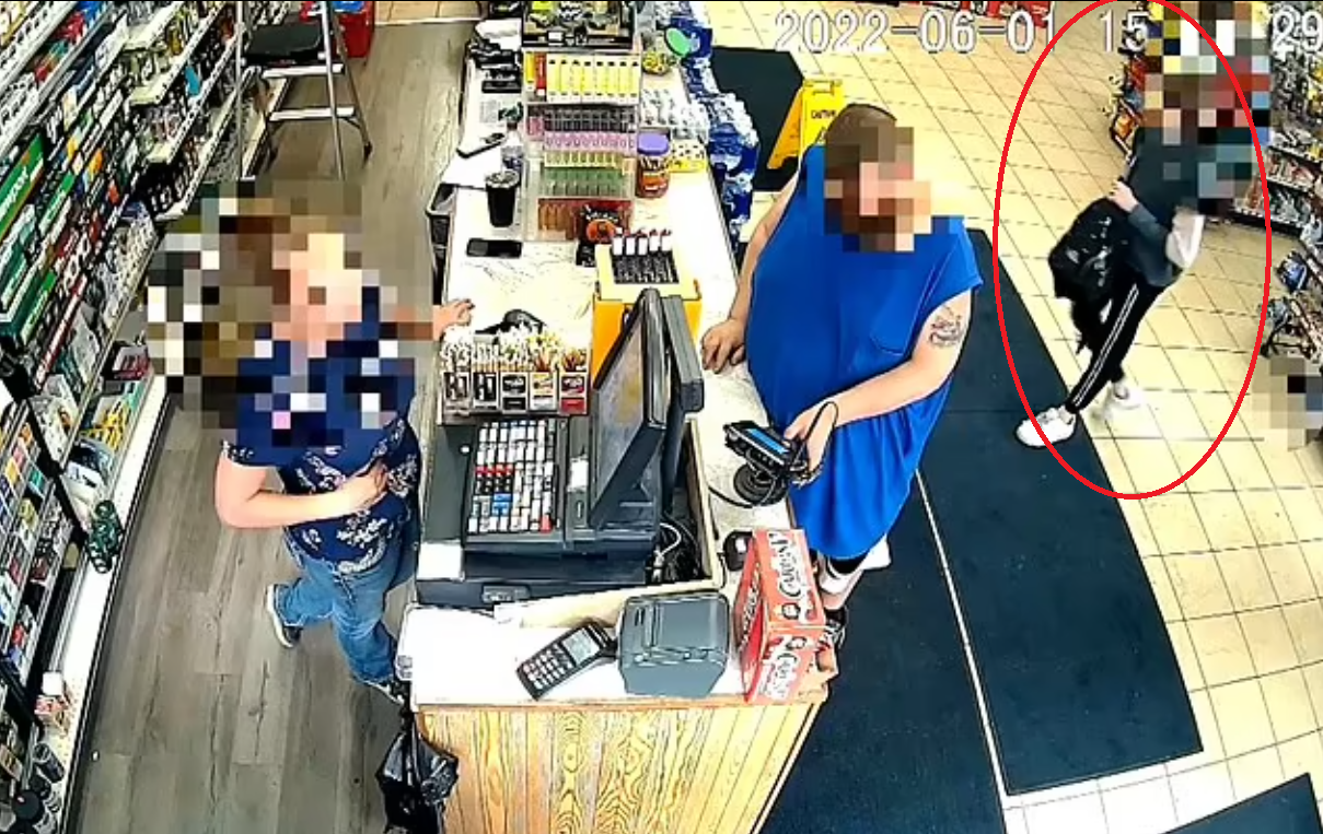 男童(紅圈)在收銀處排隊,持槍的右手一直垂下。(互聯網)