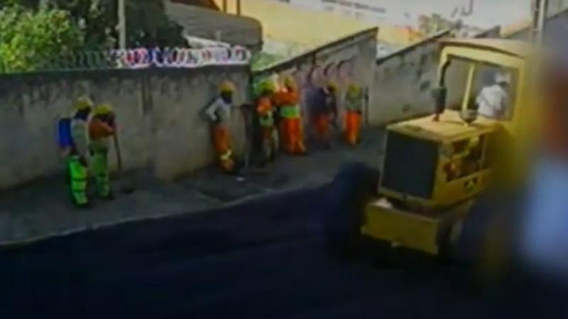 Davi與同事走到旁邊行人路,靠著牆避太陽。(YouTube)