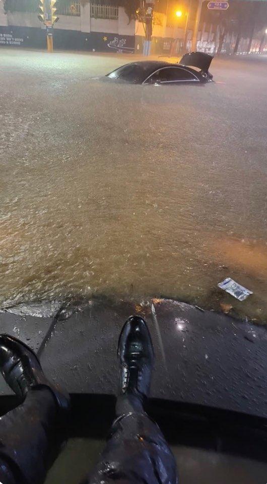 西裝男上傳了自己受困車頂的照片,從他的視角可以看見水已經淹到引擎蓋上。(Twitter)