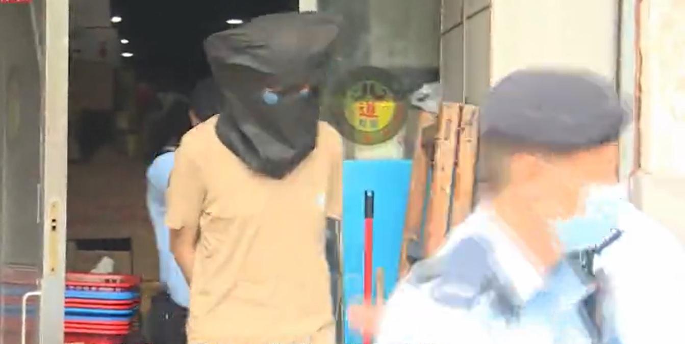 涉嫌傷人的男子被黑布蒙頭、鎖上手扣帶返警署調查。(新聞截圖)