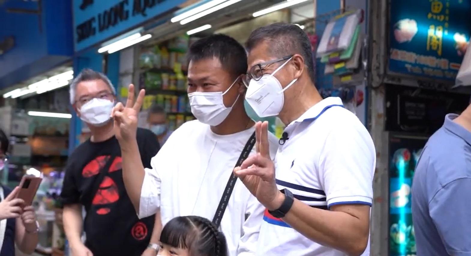 陳茂波在影片中落區搭巴士,並與市民及商戶合照。(陳茂波fb影片截圖)