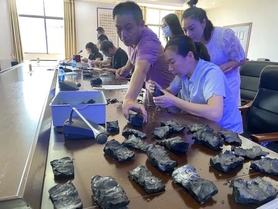 銀行職員在專家指導下,將燒成炭的現金逐張分開再鑑別。(互聯網)