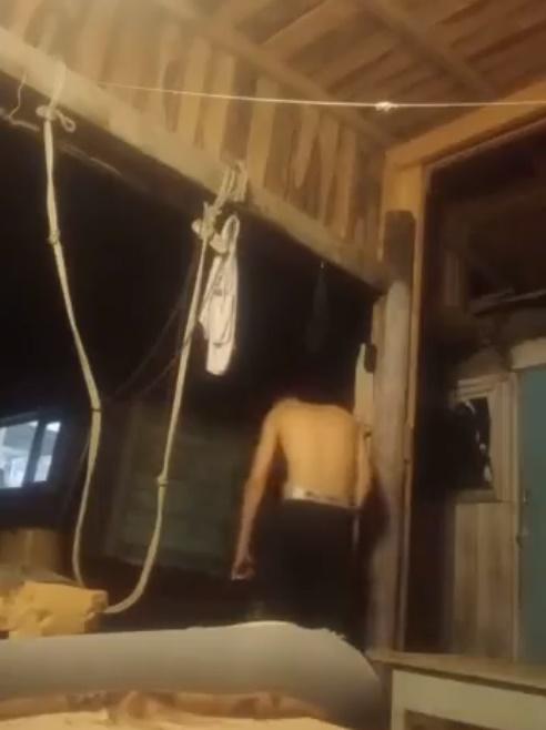 半裸男站起來,望著自己軟癱下垂的左手,慢慢走到棚屋外。(Twitter)