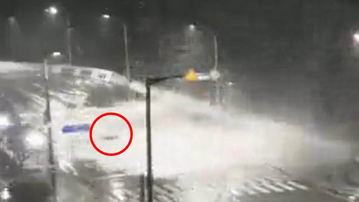 幸好他沒有被沖落海,卻被大浪沖到馬路中間。(Twitter)