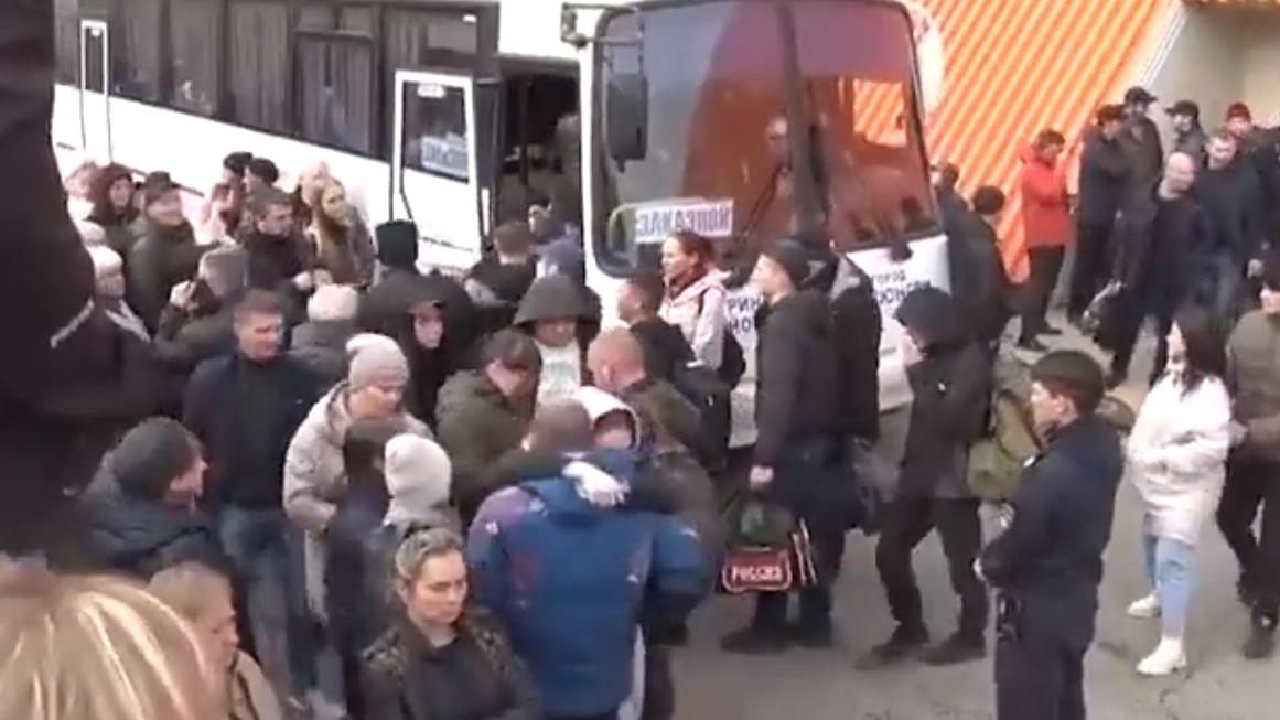 在Yakutia地區,顯示近百名俄羅斯人圍繞著幾架巴士,要與正在排隊上車的數十名男子含淚道別。(Twitter)