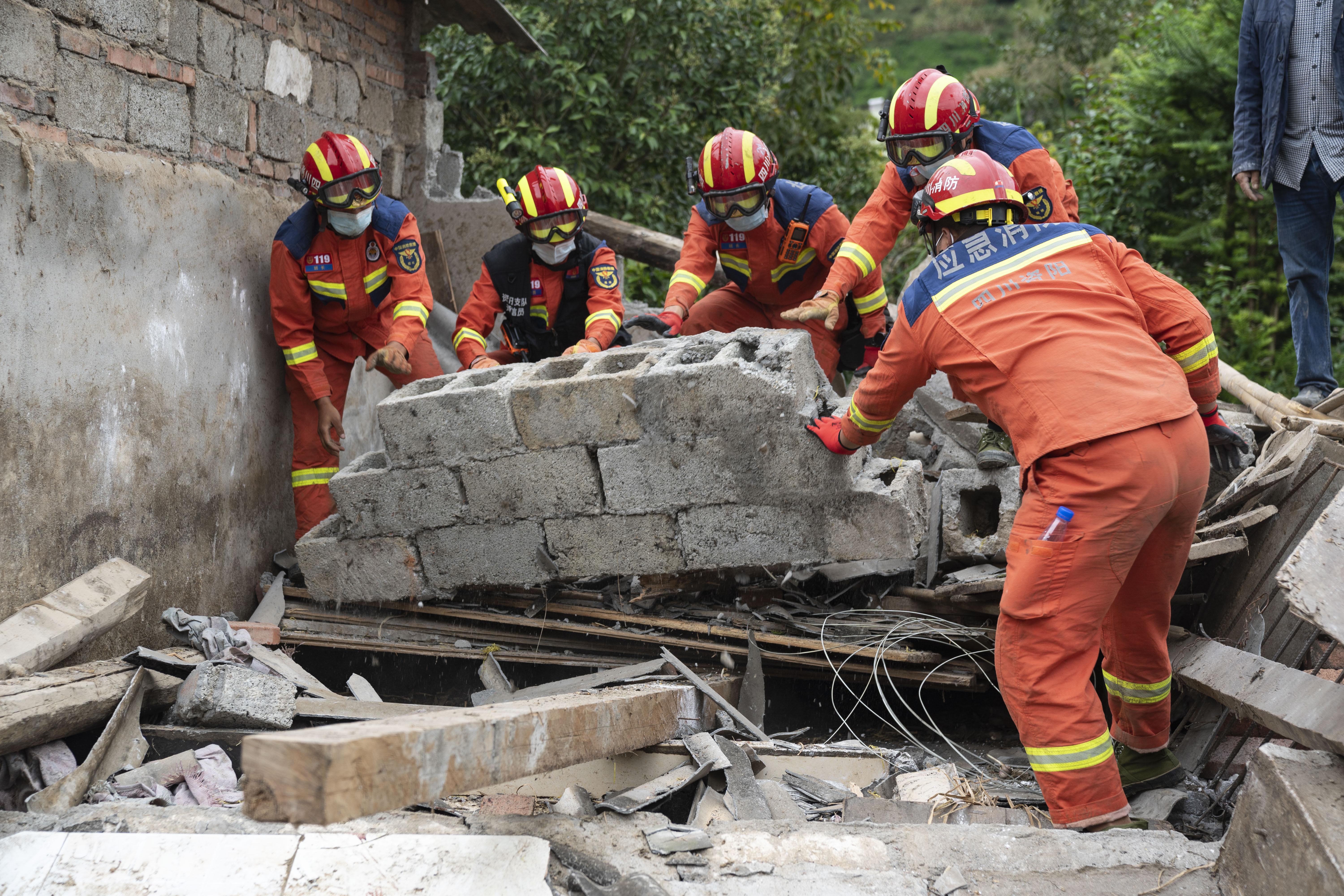 消防救援隊員在四川石棉縣幫助村民清理廢墟。(新華社圖)