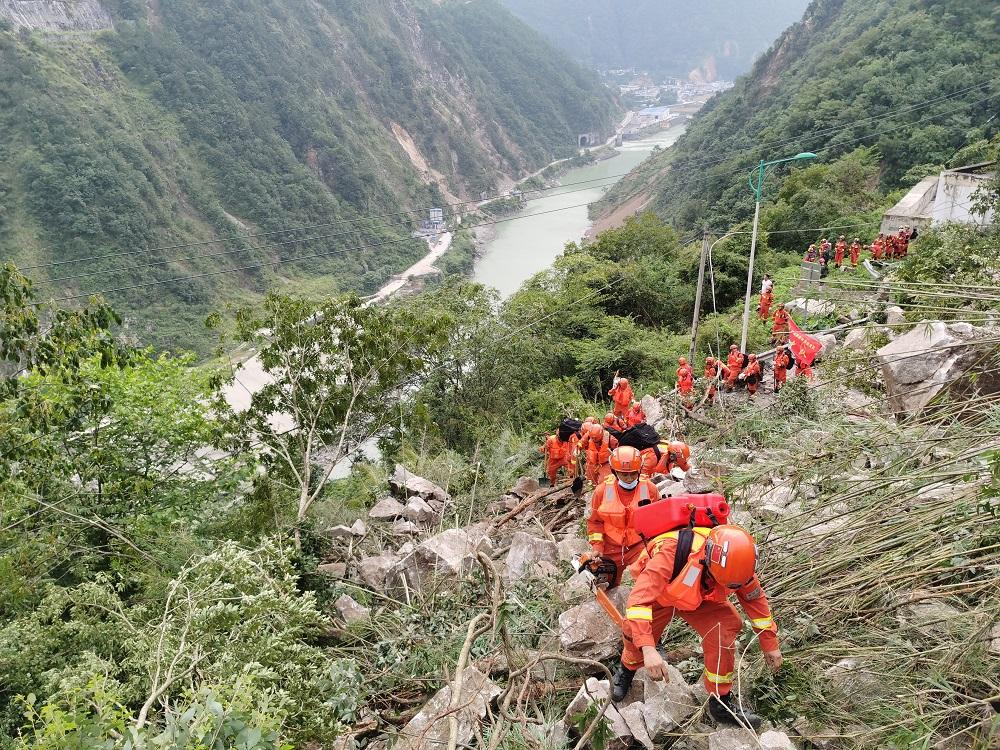 救援人員徒步進入瀘定受災村寨救人。(中新社)