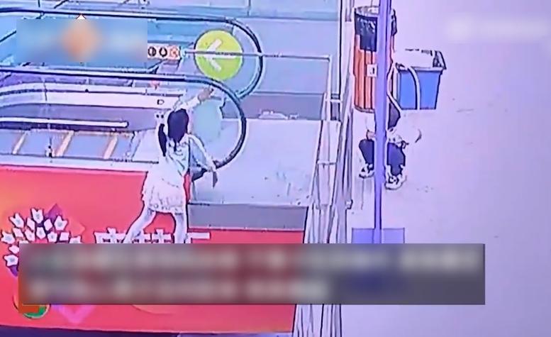 女童卡在玻璃圍欄和扶手電梯之間,雙手已無法抓緊扶手電梯。(互聯網)