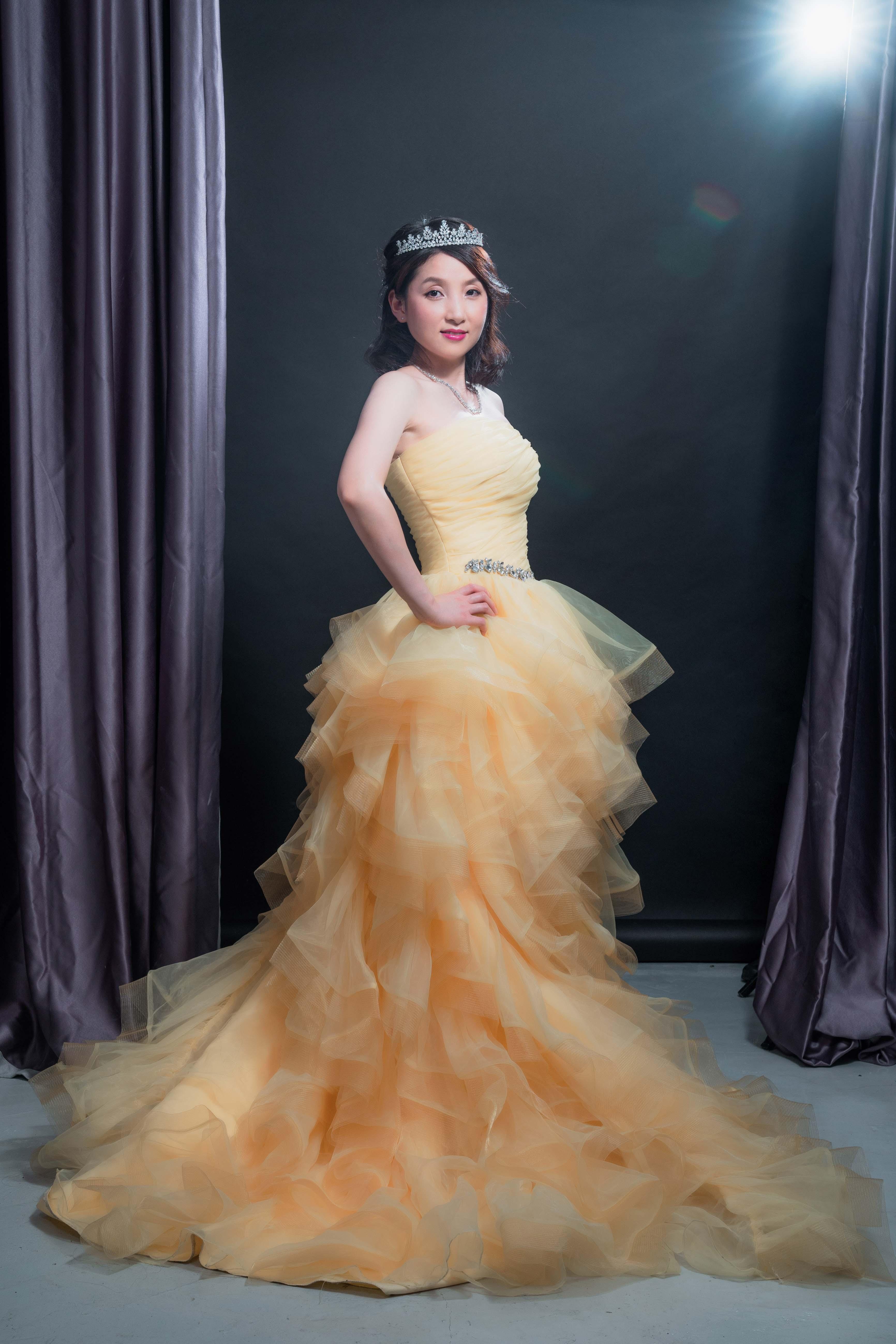 汪東娥穿上黃色晚裝,戴上「譚仔姐姐」的后冠,為店舖拍攝招聘廣告。