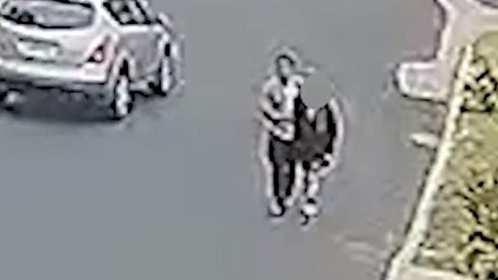 疑犯沿著公園外圍行走,一手搭在一名少女的肩膀上,一手環繞著她。警方表示,疑犯當時身上持有武器,後來在公廁中性侵得逞。(Twitter)