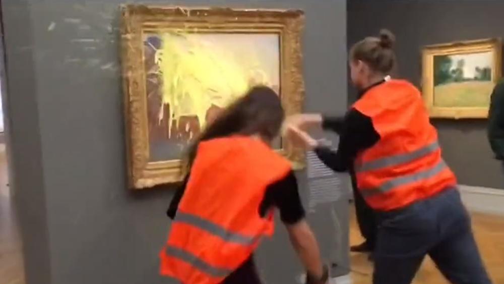 2名身穿橙色背心的示威者向莫奈名畫《乾草堆》(Les Meules)潑灑黃色物體,又用膠水將自己的手黏在牆壁。(Twitter)