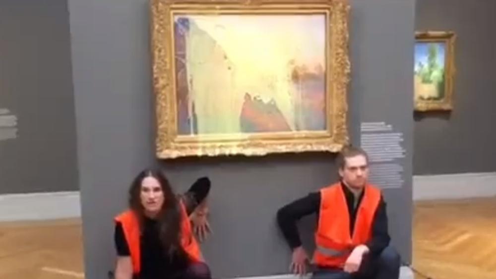 2名身穿橙色背心的示威者向莫奈名畫《乾草堆》(Les Meules)潑灑黃色物體,又用膠水將自己的手黏在牆壁。(Twitter)