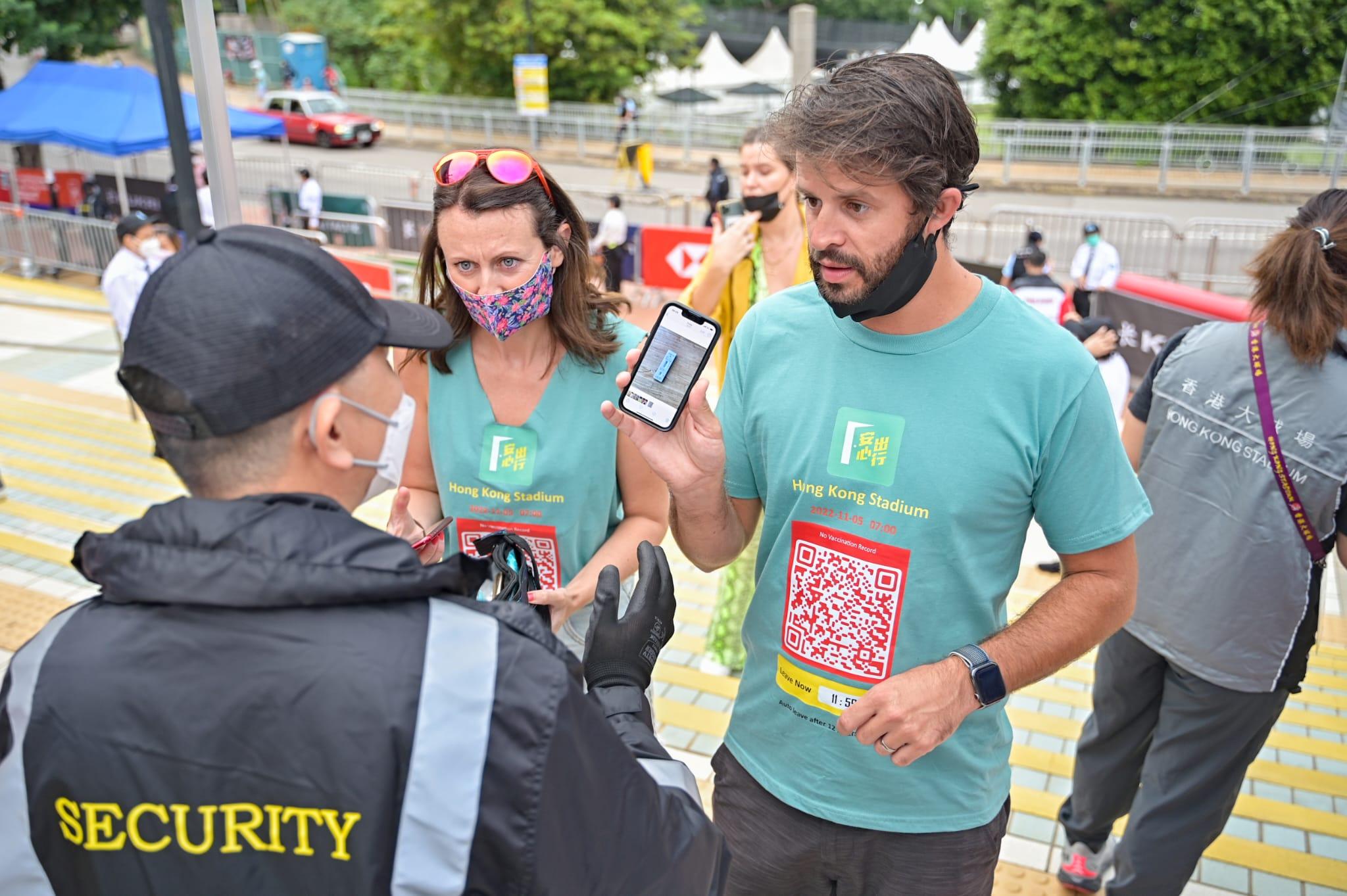 有球迷身穿印有「安心出行」的「紅碼」Tee恤進場,並在工作人員出示快測陰性記錄的照片。(李睿哲攝)