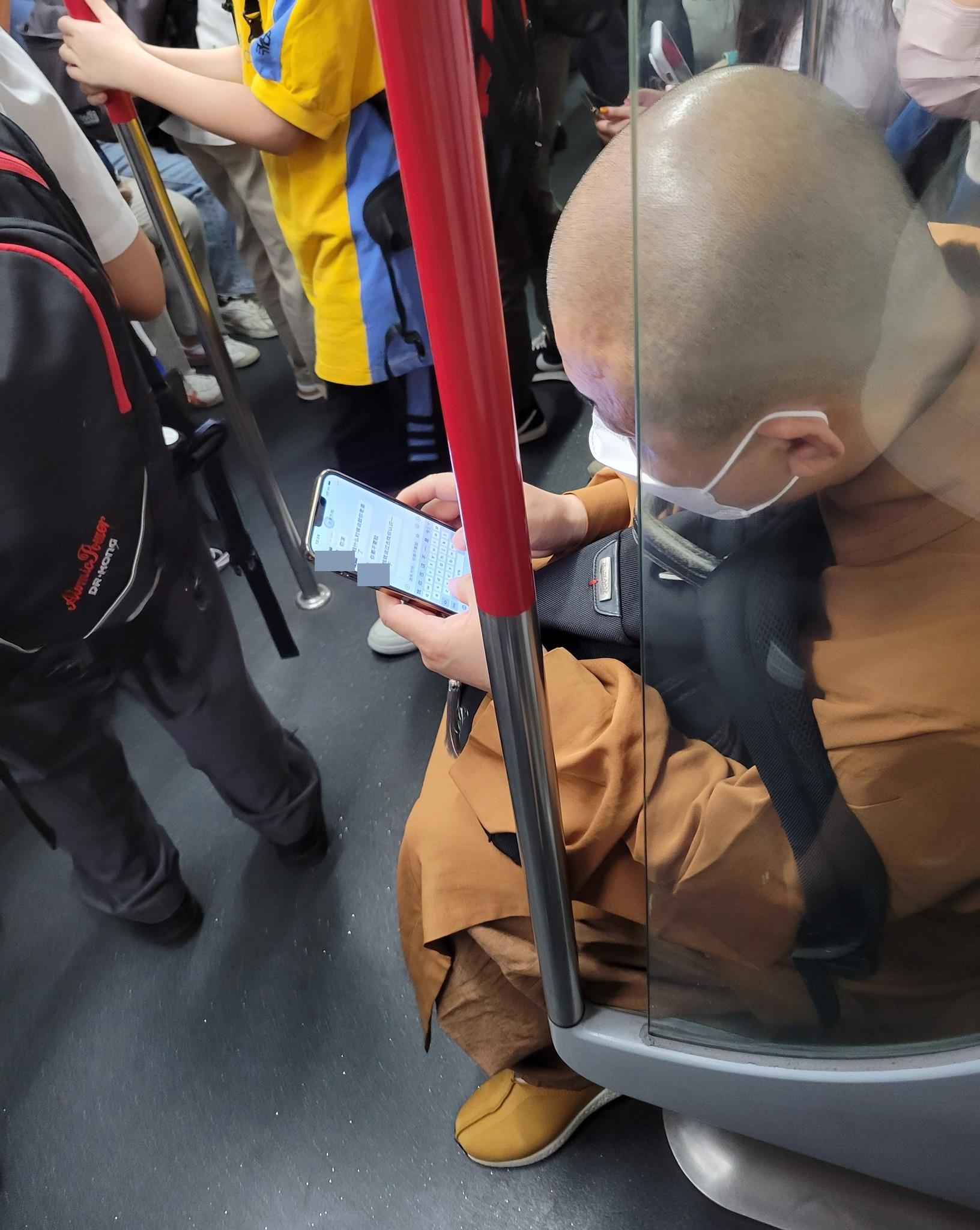 僧人打扮的男子在車廂中玩微信,內容惹來網民爭議。(香港交通及突發事故報料區@fb圖)