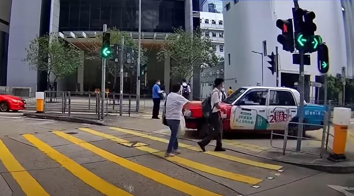 奪命的士走捷徑剷上安全島,與路人擦身而過。(影片截圖)