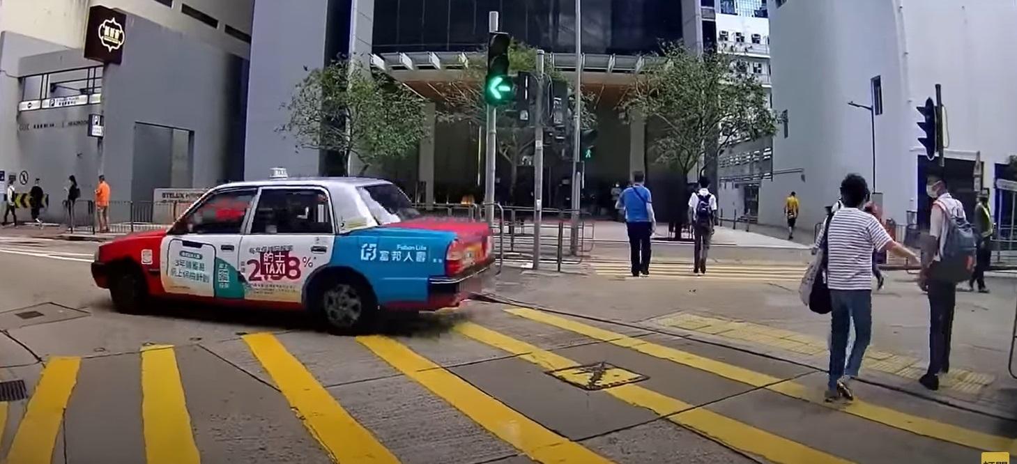 奪命的士走捷徑剷上安全島,與路人擦身而過。(影片截圖)