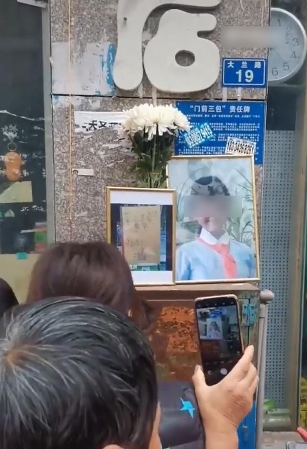 民眾在涉事文具店外擺放女童遺照和當日老闆在店門展示的習作簿照片。(互聯網)