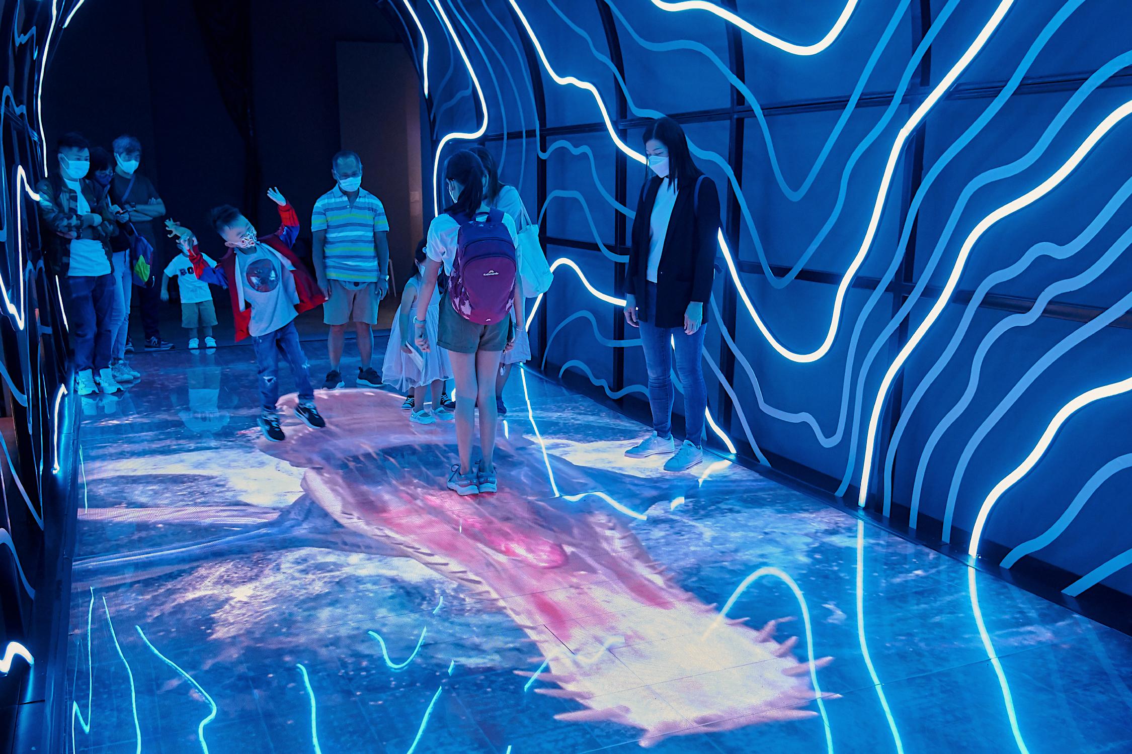 參觀者在「時間隧道」欣賞有關史前生物的影片。