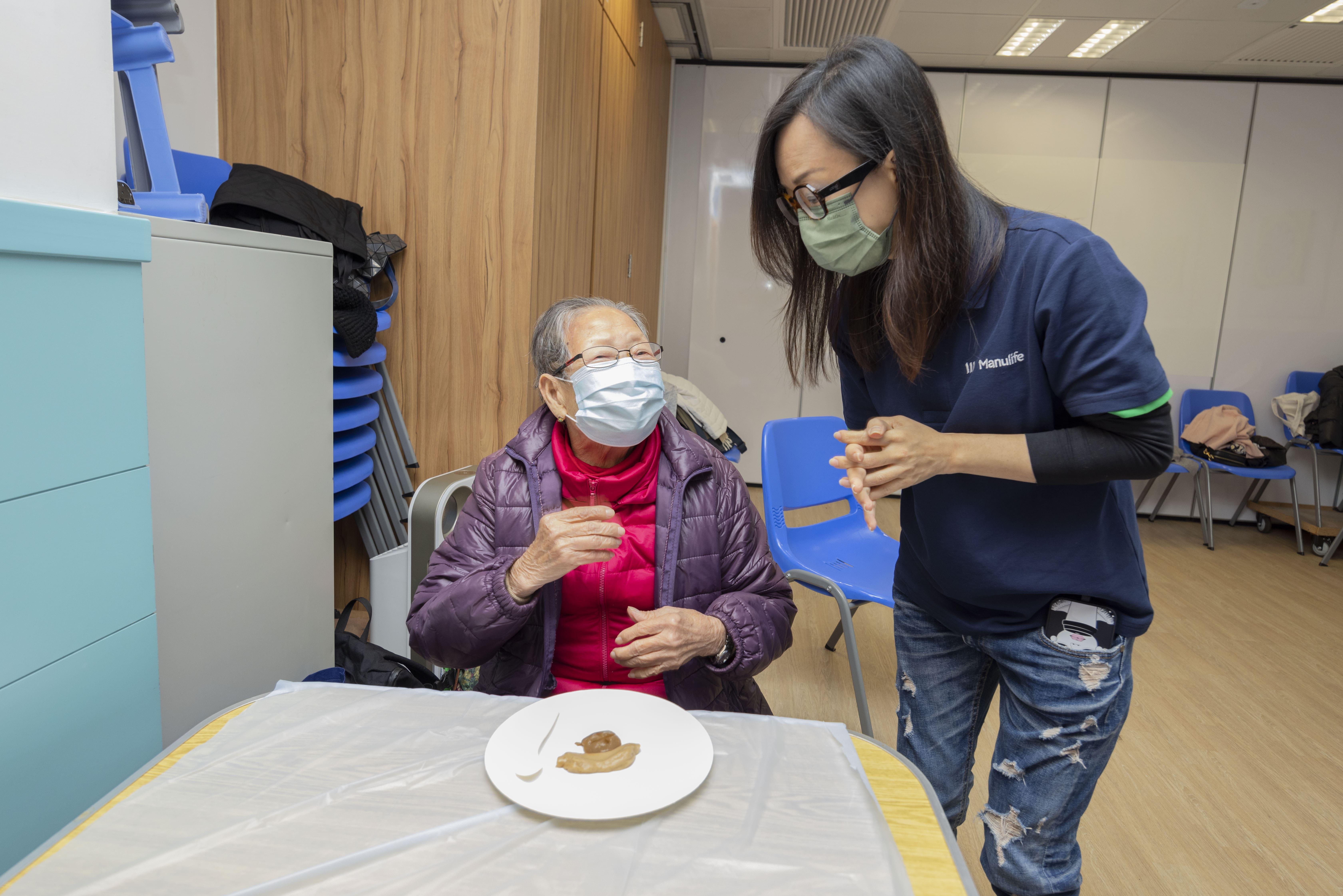 宏利香港義工向長者介紹養生軟餐。