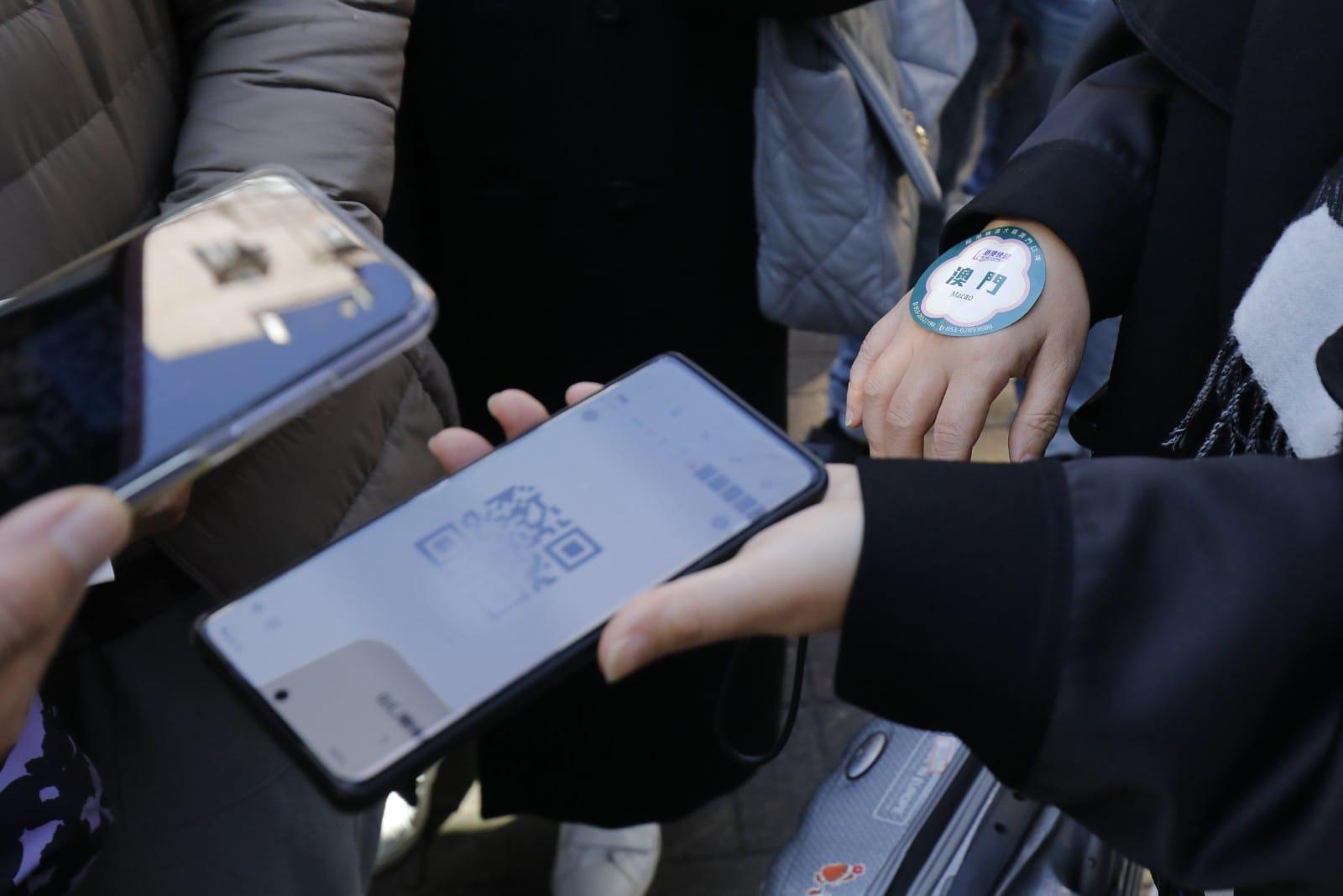 直通巴士職員即場檢查乘客的紙本核酸證明,確認陰性結果後會派發貼紙識辨。(林俊源攝)