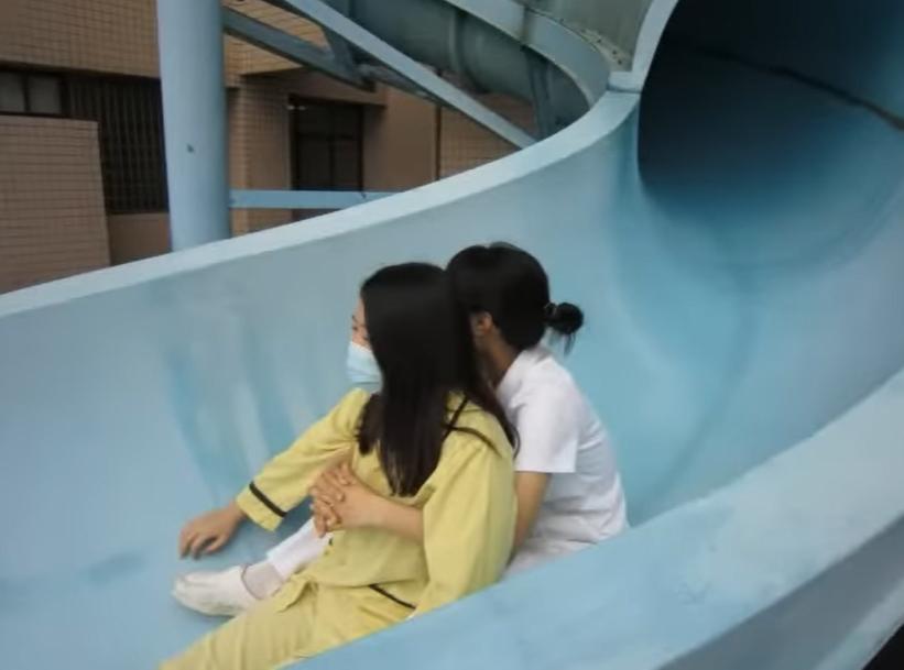 病人由醫護人員抱著滑下逃生滑梯。(影片截圖)