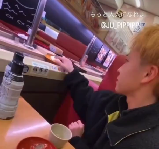 青年用沾上口水的手指觸摸壽司。(影片截圖)