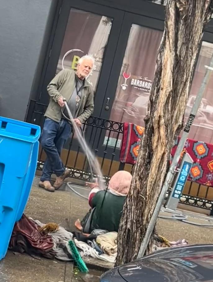 畫廊老闆Collier Gwin用凍水直射在畫廊外坐在行人路上的1名女露宿者。(Twitter)