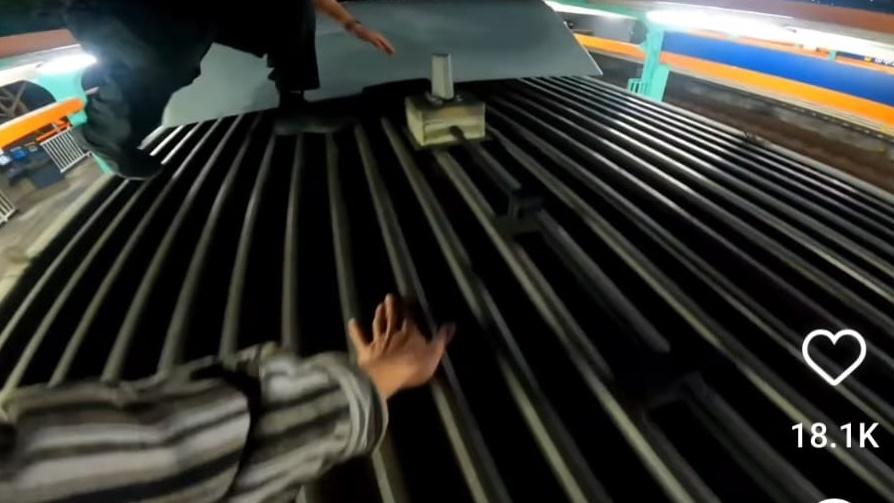 2青年待一列輕鐵到站的時再跳上車頂,再抓住車頂突起的部分。(IG)