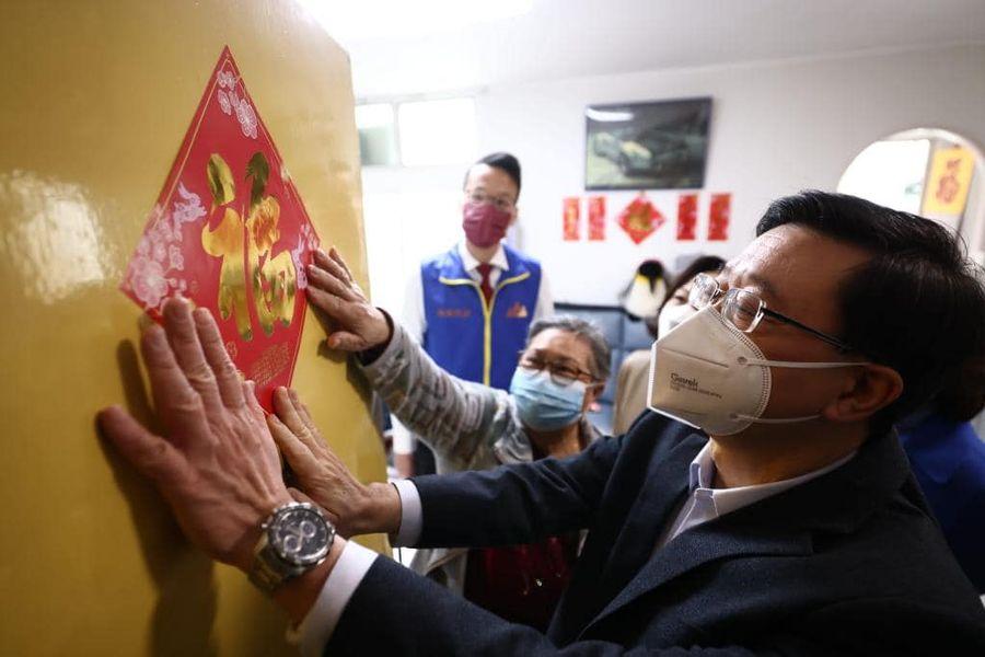 特首李家超到青衣長亨邨上門派福袋,並為市民貼福字揮春。(李家超fb圖)