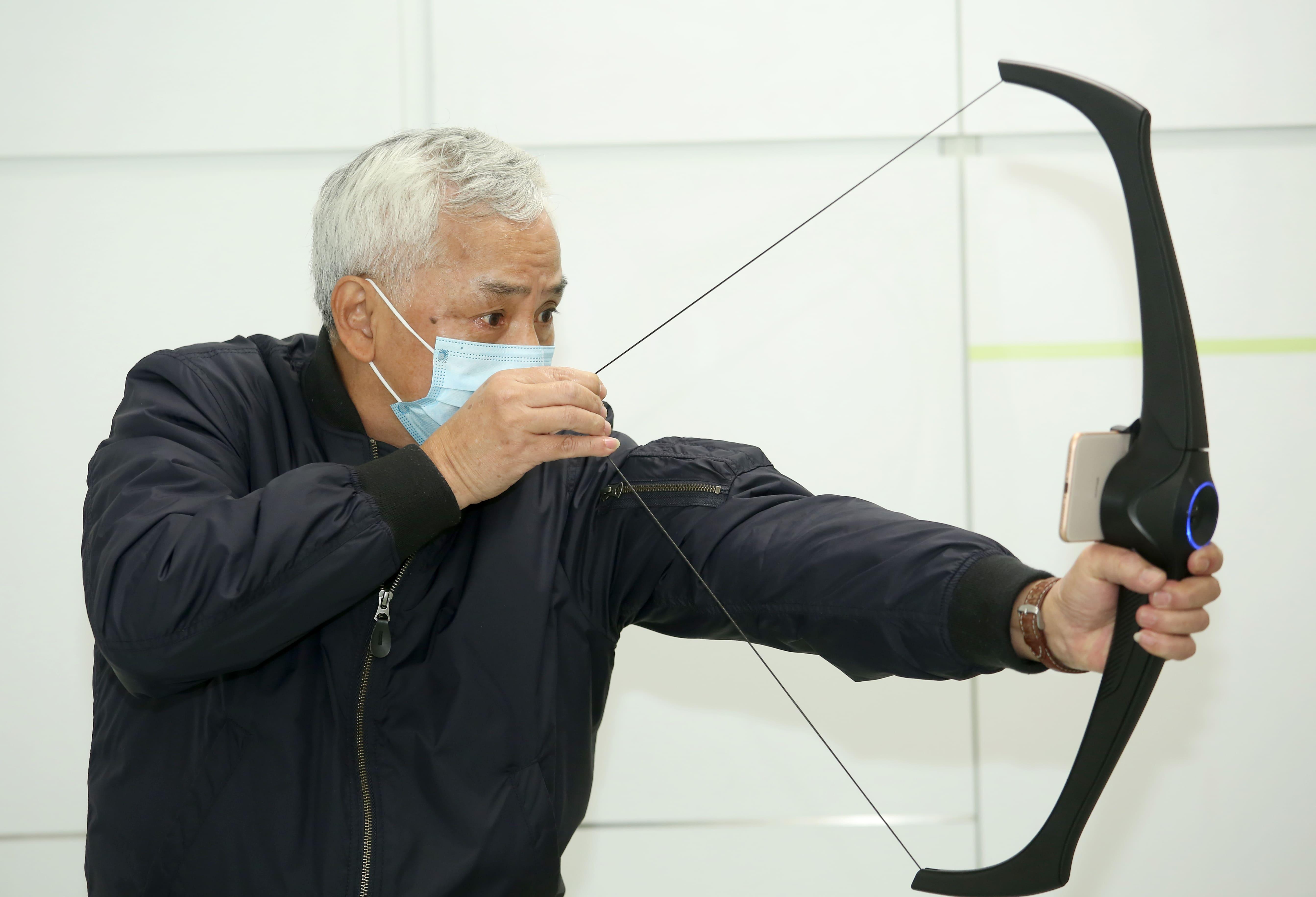 Raymond試範其中一項樂齡科技——射箭。