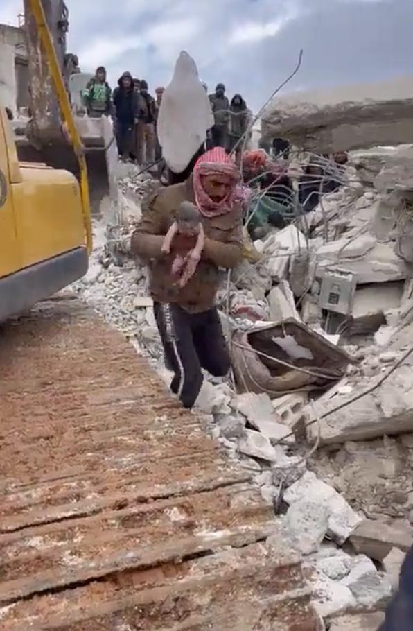 一名男子帶著剛出生的嬰兒,嬰兒全身赤裸並布滿塵土,男子帶著他趕緊前往尋求醫療協助。(Twitter)