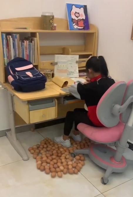 河北一位媽媽將雞蛋放在女兒腳下,女兒終於坐定定做功課。(抖音)