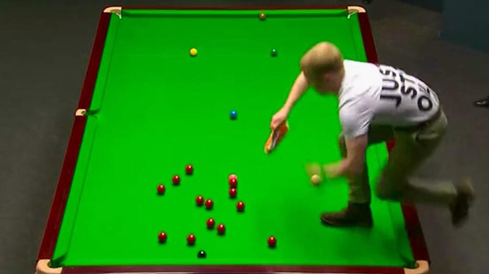 環保組織男成員突然闖入並跪在桌球枱上向灑上橙色粉末,令比賽一度暫停。(Twitter)