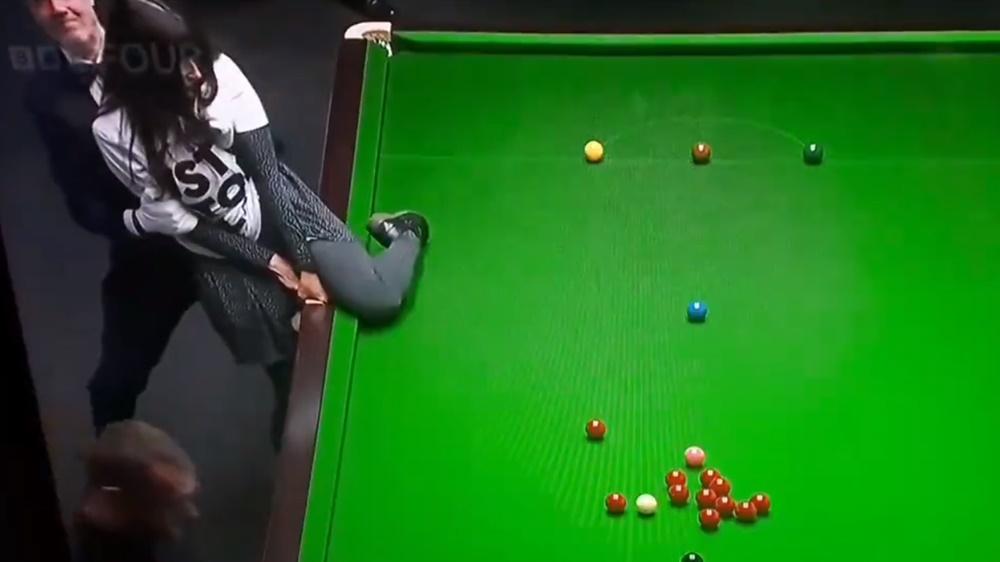 另一名環保組織女成員到另一張桌球枱,試圖用膠水將自己黏住桌球枱,隨即被在場保安人員阻止。(Twitter)