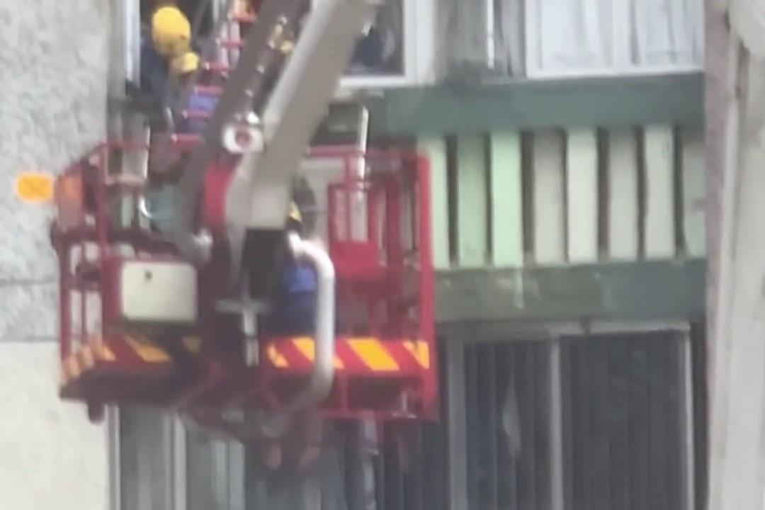 順天邨有女子危坐外牆晾衫架,街坊直擊消防員合力救人過程。(網上影片截圖)